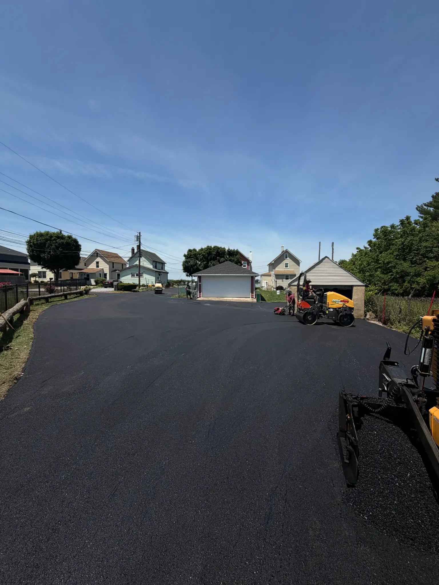 Driveways Express crew compacting a newly paved asphalt driveway with a roller and plate compactor