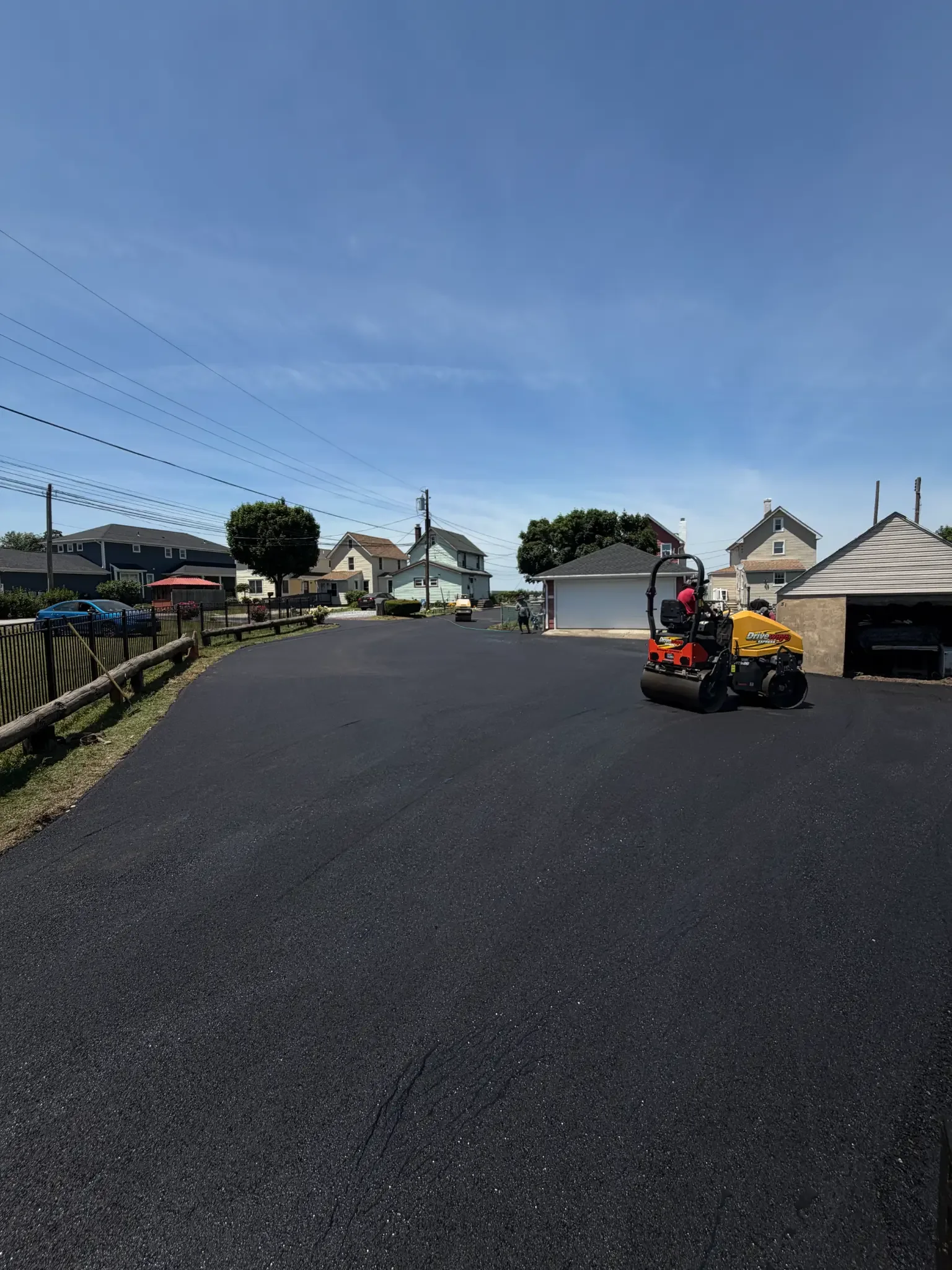 Driveways Express roller compacting fresh asphalt on a residential driveway